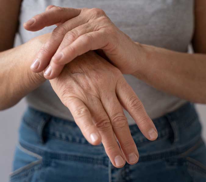 Close-up of a person holding their right wrist.