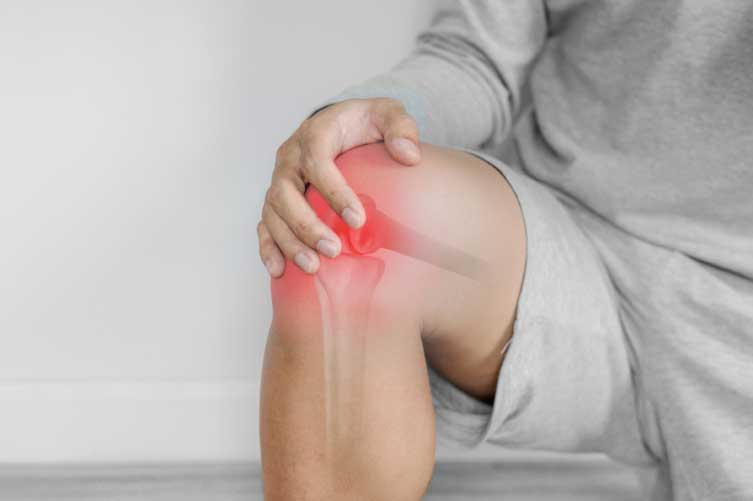 Person pressing their right knee due to pain or injury.