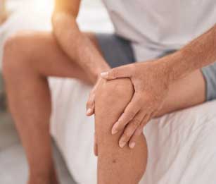A patient holding their left knee in pain.
