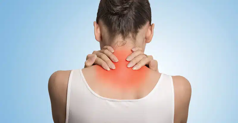 A woman holding the back of her neck with her hands due to severe pain caused by fibromyalgia.