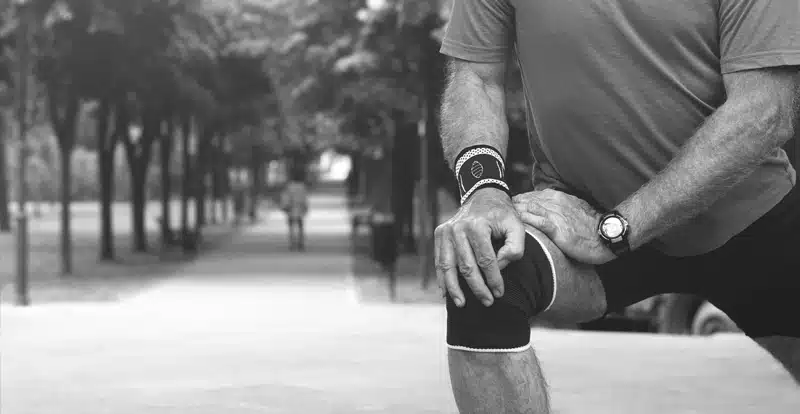 Close-up of a man stretching his right knee.